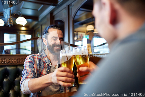 Image of happy male friends drinking beer at bar or pub