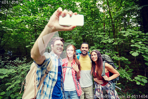 Image of friends with backpack taking selfie by smartphone