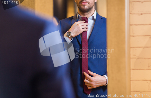 Image of close up of man trying tie on at mirror