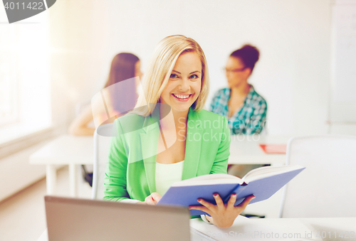 Image of smiling young girl reading book at school