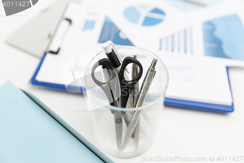 Image of close up of cup with scissors and pens at office