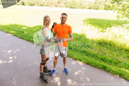 Image of happy couple with roller skates riding outdoors
