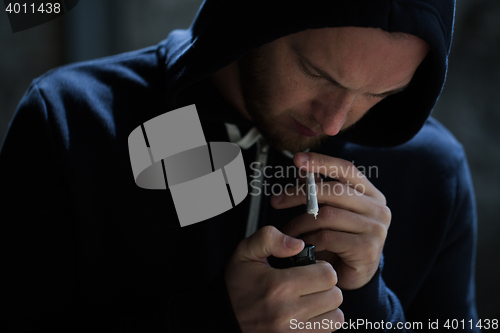 Image of close up of addict lighting up marijuana joint