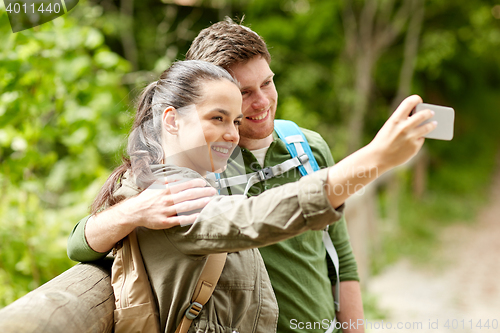 Image of couple with backpacks taking selfie by smartphone