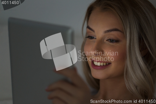 Image of young woman with tablet pc in bed at night