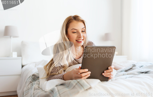 Image of happy young woman with tablet pc in bed at home