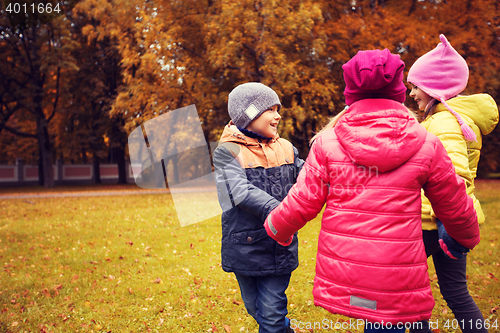 Image of children holding hands and playing in autumn park
