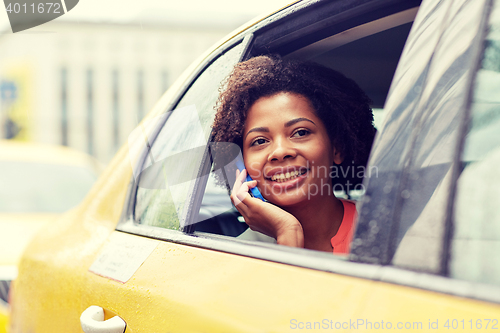 Image of happy african woman calling on smartphone in taxi