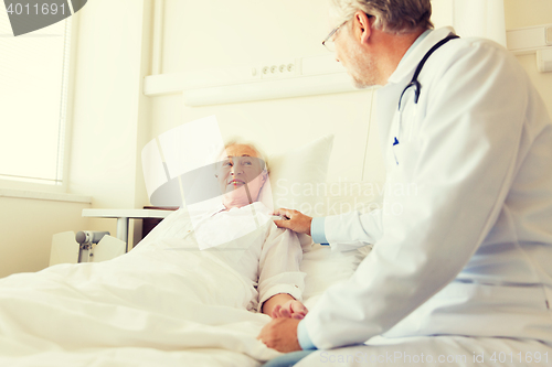 Image of doctor visiting senior woman at hospital ward