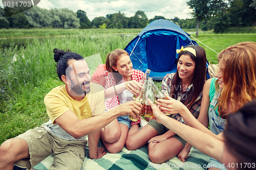 Image of happy friends with tent and drinks at campsite