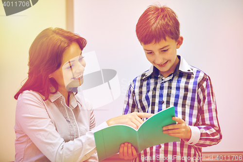 Image of school boy with notebook and teacher in classroom