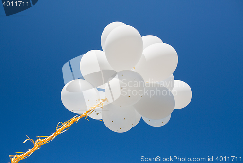 Image of close up of white helium balloons in blue sky