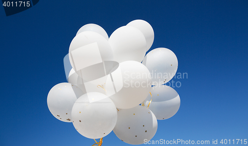 Image of close up of white helium balloons in blue sky