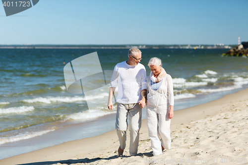 Image of happy senior couple holding hands on summer beach