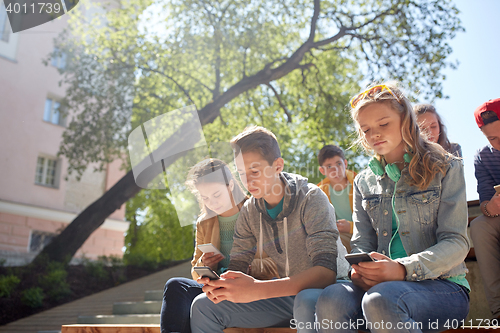 Image of group of teenage friends with smartphones outdoors