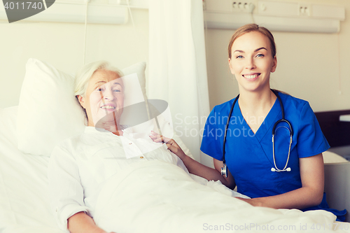 Image of doctor or nurse visiting senior woman at hospital