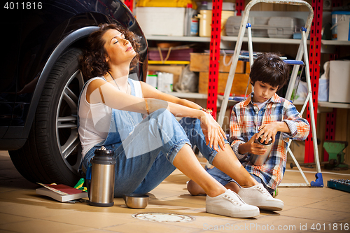 Image of resting mechanic woman and boy with thermos