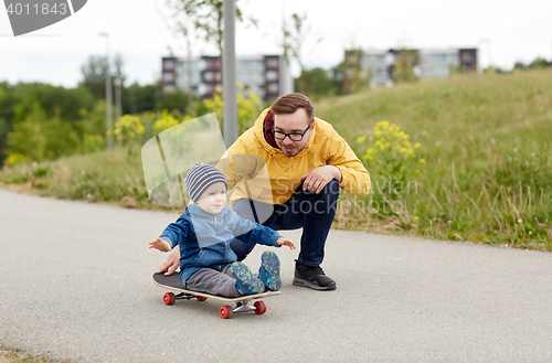 Image of happy father and little son riding on skateboard