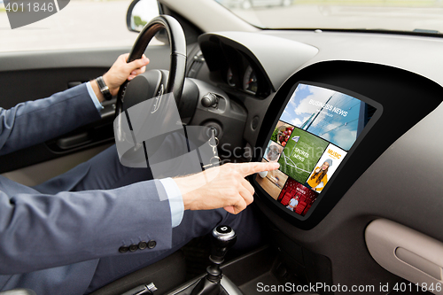 Image of man driving car with news on board computer