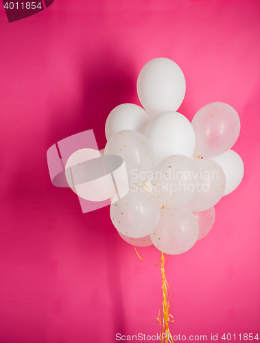 Image of close up of white helium balloons over pink