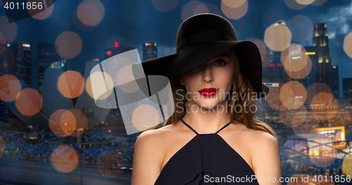 Image of beautiful woman in black hat over night city