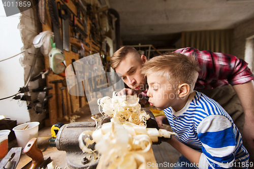 Image of father and little son with wood plank at workshop