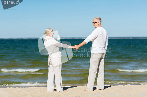 Image of happy senior couple holding hands on summer beach