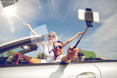 Image of happy couple in car taking selfie with smartphone