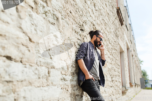 Image of smiling man with smartphone calling on city street