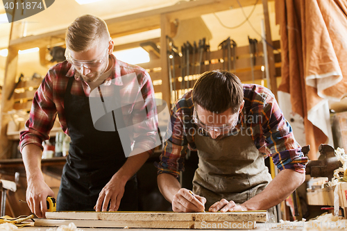 Image of carpenters with ruler and wood plank at workshop