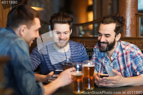 Image of male friends with smartphones drinking beer at bar