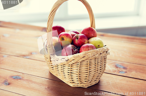 Image of close up of basket with apples on wooden table