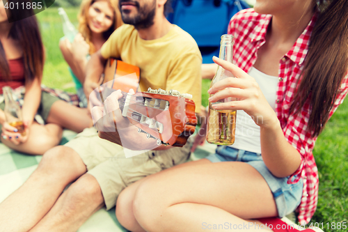 Image of happy friends with drinks and guitar at camping