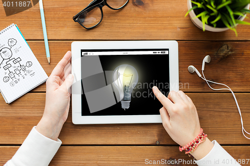 Image of close up of woman with tablet pc on wooden table