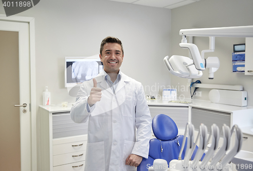 Image of happy male dentist showing thumbs up at clinic