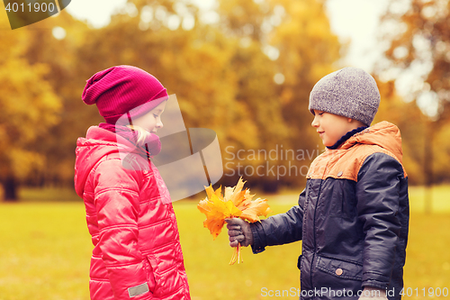 Image of little boy giving autumn maple leaves to girl