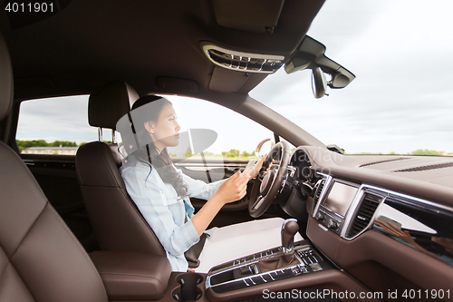Image of happy woman driving car with smarhphone