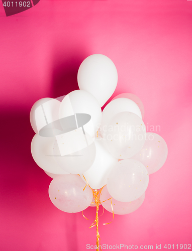 Image of close up of white helium balloons over pink