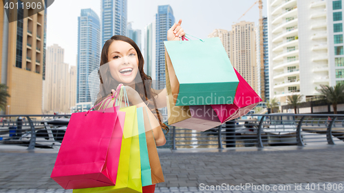 Image of happy woman with shopping bags over dubai city