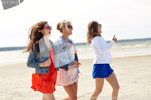 Image of group of smiling women in sunglasses on beach