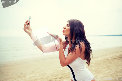 Image of young woman taking selfie with smartphone