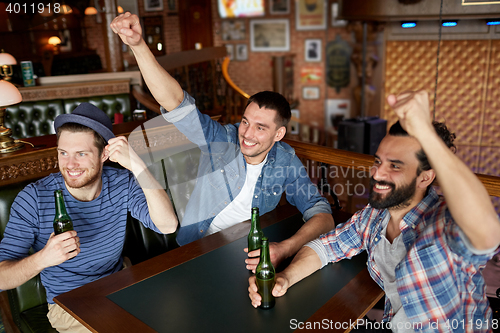 Image of happy male friends drinking beer at bar or pub