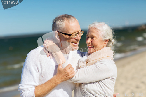 Image of happy senior couple hugging on summer beach