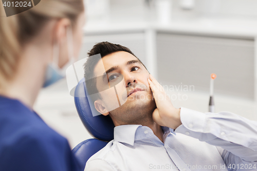 Image of female dentist and male patient with toothache