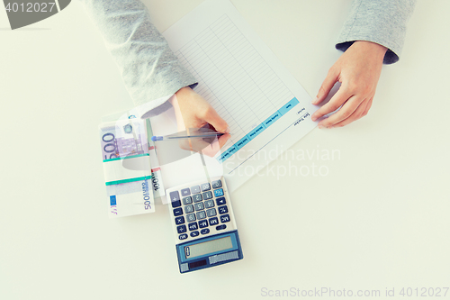 Image of close up of hands counting money with calculator