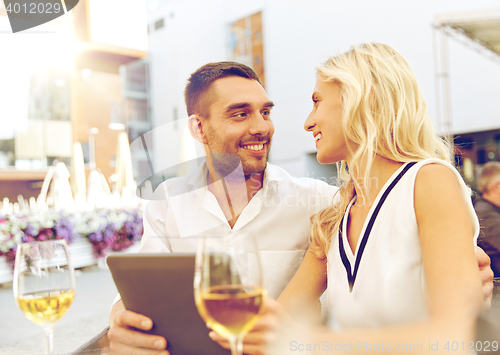 Image of happy couple with tablet pc at restaurant terrace