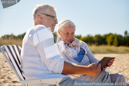 Image of happy senior couple with tablet pc on summer beach