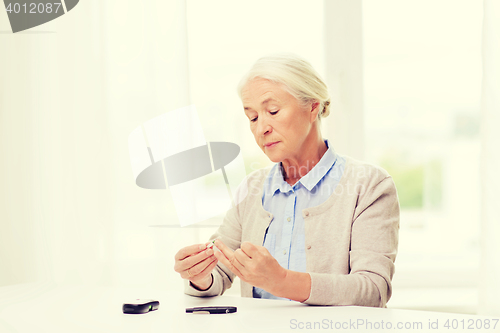 Image of senior woman with glucometer checking blood sugar