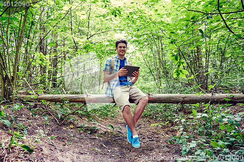 Image of happy man with backpack and tablet pc in woods
