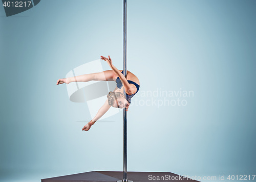 Image of The strong and graceful young girl performing acrobatic exercises on pylon